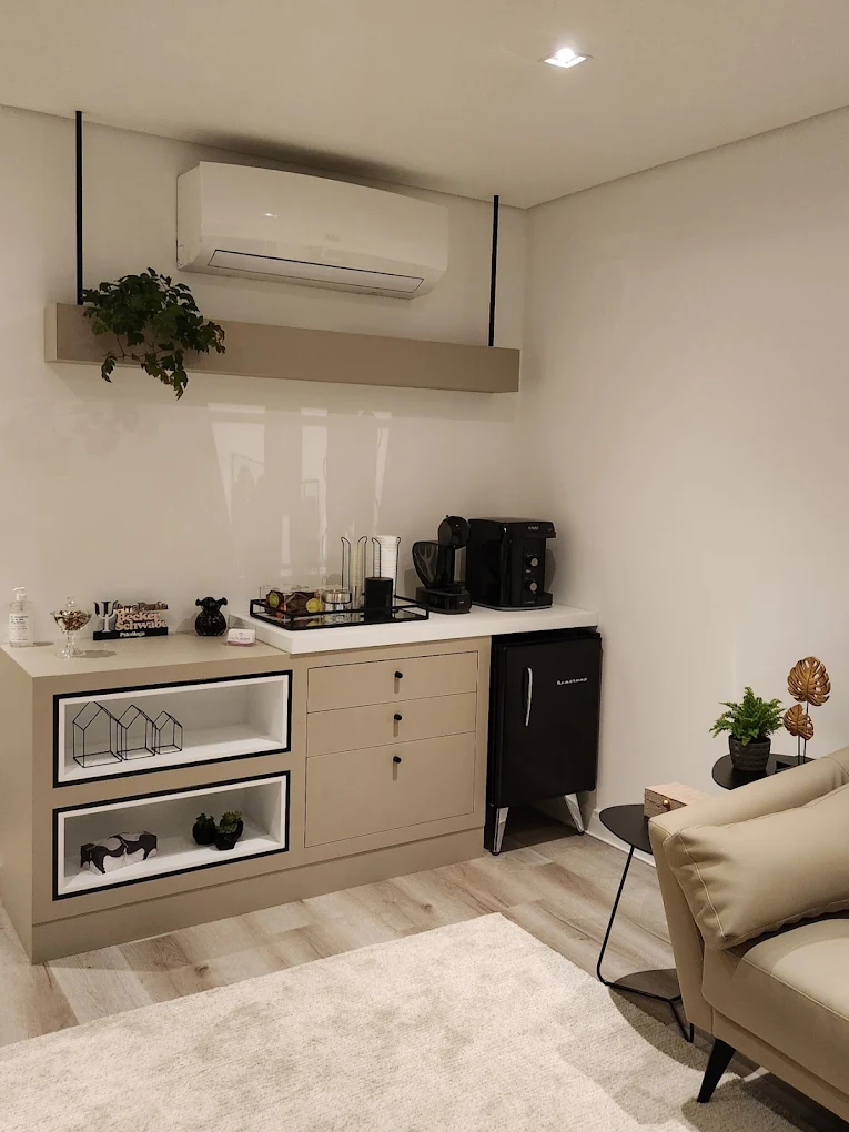 Recepção do consultório com bancada clara, plantas e espaço para café